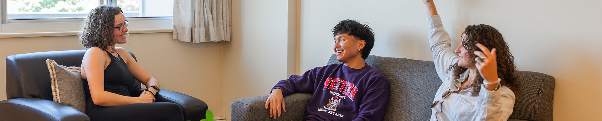 Three students sitting in living talking